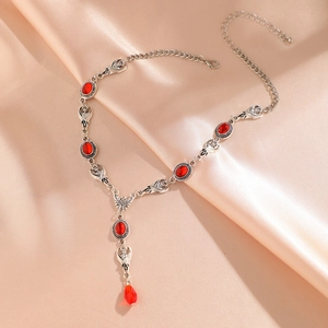 Gothic silver Y-necklace with red oval gems and teardrop pendant on silk background