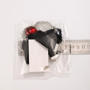 Details eines Gothic-Chokers mit rotem Edelstein und silberner Fassung mit Lineal zum Maß