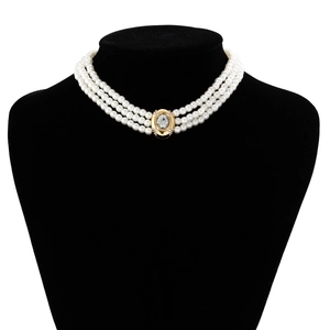 Détail d'un collier de perles à trois rangs avec pendentif en cristal doré sur un buste