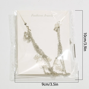 Detail of beaded choker featuring layered chains and pearls on a branded display card