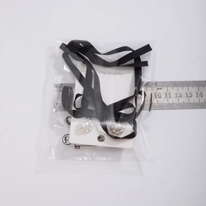 Detailed view of pearl flower earrings with black ribbon bows on display card