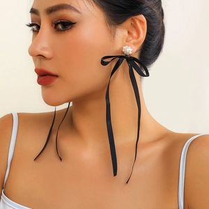 Elegant long black ribbon bow earrings with pearl flower studs worn by a model
