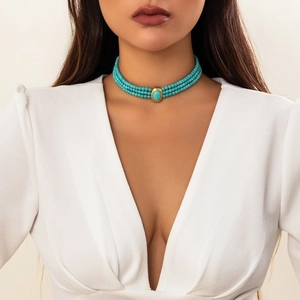 Détail du choker à trois rangs de perles turquoise avec un grand bijou central doré