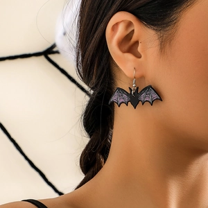 Detail shot of bat-shaped Halloween earrings with purple accents on a model