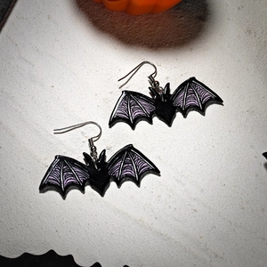Detail of acrylic bat earrings with purple wing textures and silver hooks for Halloween