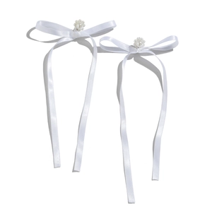 Detail of white ribbon bow earrings with faux pearl flower centers and long tassels