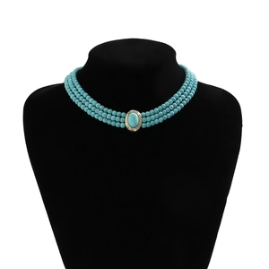 Gros plan détaillé du collier ras du cou à trois rangs de perles turquoise et pierre ovale