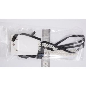 Close-up of double-layer faux pearl necklace with black silk ribbons and measuring scale