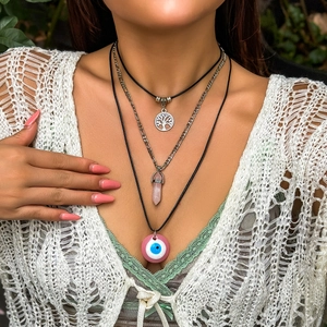 Nahaufnahme böhmischer Lagenhalsketten mit rosa Kristall und Evil Eye Anhänger am Modell