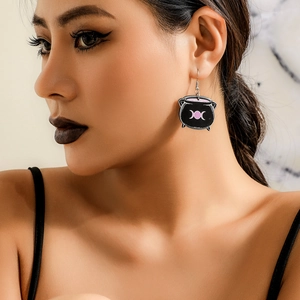 Macro detail of witch cauldron earring with pink triple moon logo on gothic dark acrylic