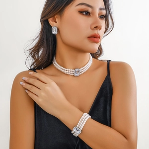 Gros plan du collier ras-du-cou à trois rangs de perles et boucles d'oreilles sur modèle