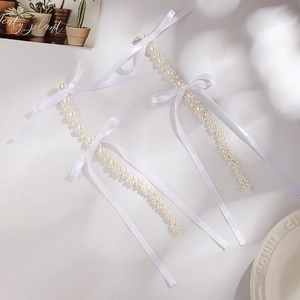 Detailed shot of long pearl tassel earrings with elegant white silk ribbon bows