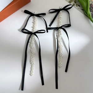 Detail of fabric bow earrings with multi-strand pearl tassels and elegant black ribbon