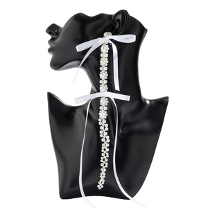 Detail of long drop tassel earrings with white pearls and satin ribbon bows for women
