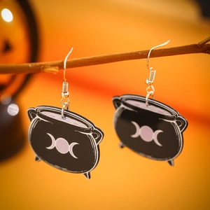 Macro detail of witch cauldron acrylic earrings with triple moon symbol and silver hooks