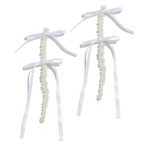 Detail of white pearl woven tassels with satin bows on elegant floral earrings