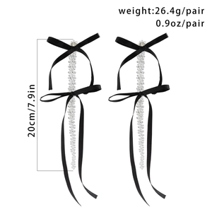 Detailed view of oversized black fabric bow earrings with crystal beaded fringe tassels