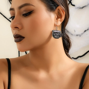 Detail of a black acrylic witch cup earring featuring Witches Brew text on a model