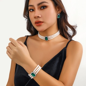 Gros plan du collier de perles et parure émeraude sur mannequin en velours noir