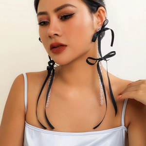 Detail of long drop earrings featuring a black ribbon bow and faceted crystal beads