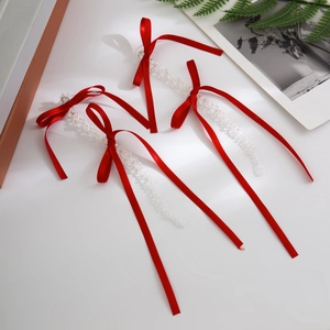 Detailed view of red ribbon bow earrings with transparent crystal bead tassels