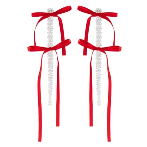 Macro view of crystal beaded tassel earrings with vibrant red satin ribbon bows