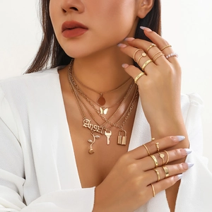 Set collana a strati dorata con farfalla, lucchetto e anelli di perle coordinati