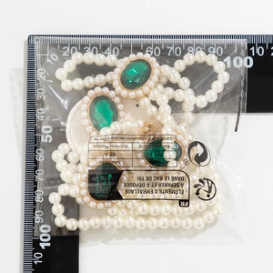 Détail d'un collier de perles multicouche avec pierres précieuses vertes sous emballage