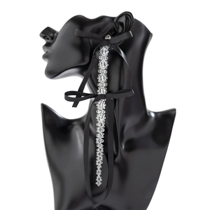 Detail of long fringe earrings with crystal beads and black satin ribbon bows