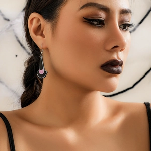 Close-up of a black acrylic witch hat earring with purple detail on a female model