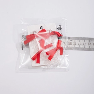 Detailed view of beaded bow hair accessory with red satin ribbons on display card