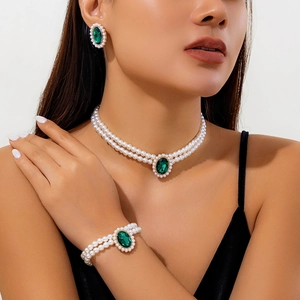 Détail d'un ras-du-cou en perles et d'un collier émeraude portés par un mannequin