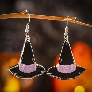 Detail of acrylic witch hat earrings with star pattern hanging on a branch