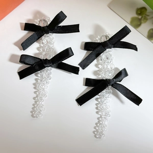 Detail of long crystal bead drop earrings with black satin bows in a vintage sweet style