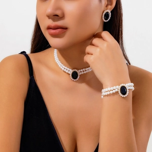 Gros plan du collier choker en perles avec pierre noire ovale et monture dorée
