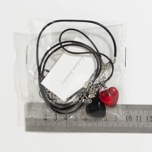 Close-up of heart-shaped magnetic necklaces with red and black pendants on card