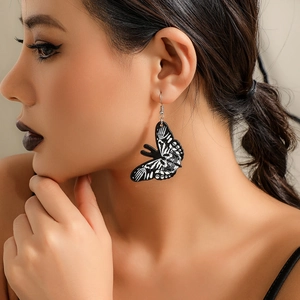 Close-up of black acrylic butterfly earrings with white skeleton print on a model