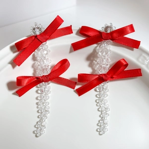 Close-up of elegant red ribbon bows with transparent crystal beads on white ceramic plate