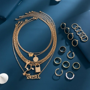 Collana a strati dorata con ciondoli a farfalla e set di anelli su sfondo blu scuro