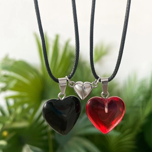 Close-up of magnetic heart pendants in black and red on woven cords for couples