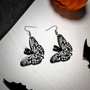 Macro view of gothic acrylic butterfly earrings with skull patterns and bone textures
