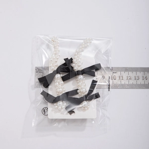 Detail showing white faux pearl beads and black satin ribbon bow earrings with 7.5cm ruler