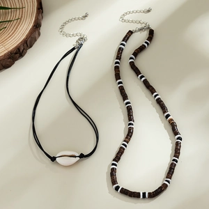 Nahaufnahme der Boho-Muschelkette und Holzperlen auf minimalistischem Holzscheiben-Hintergrund