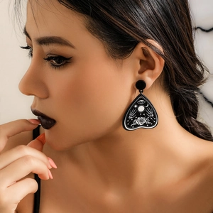 Close-up of gothic droplet earring with mystic moon and palm symbols worn by a model