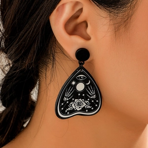 Close-up of gothic acrylic teardrop earrings with skull hand and moon occult patterns