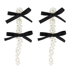 Close-up of pearl bow hair clips with black silk ribbons and elegant woven bead fringe