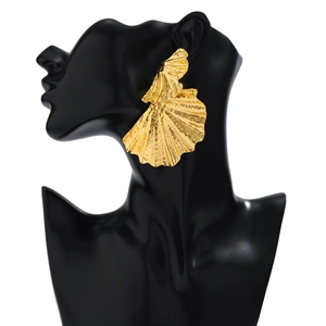 Dettaglio di orecchini a foglia di ginkgo dorati con texture su espositore nero