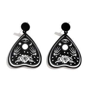 Close-up of heart-shaped Ouija acrylic earrings with gothic eye and moon symbols