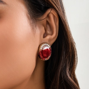 Macro shot of gothic oval stud earrings with red gemstone and sparkling crystal halo