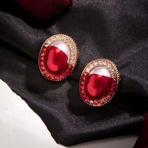 Detail of vintage oval stud earrings with red gems and pearls on black silk fabric
